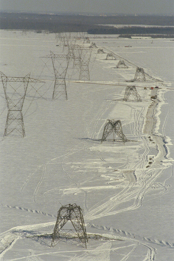 A photograph of several transmission towers after the storm, all brought down by the weight of the ice and the connections between themselves.